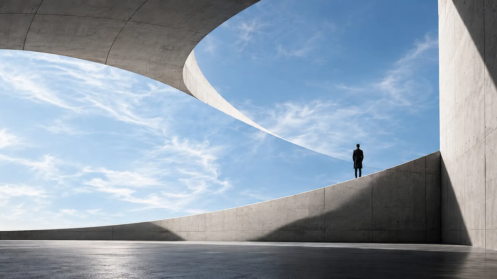 Curved concrete architecture opening toward a blue sky